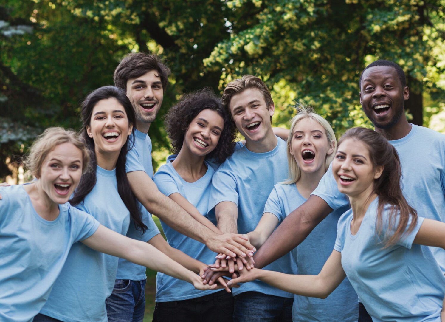 Group of people smiling with hands together.